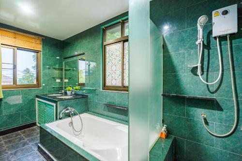 a green bathroom with a tub and a sink at ไอทะเล พูลล่า หัวหิน I-Talay Poolvilla huahin in Hua Hin