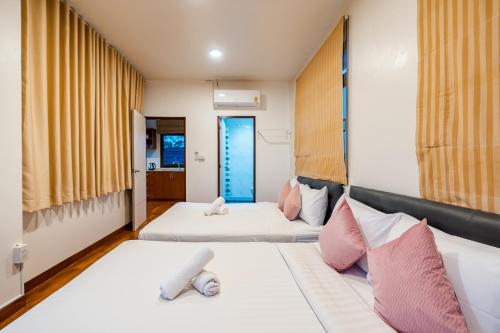 two beds in a room with yellow curtains at ไอทะเล พูลล่า หัวหิน I-Talay Poolvilla huahin in Hua Hin