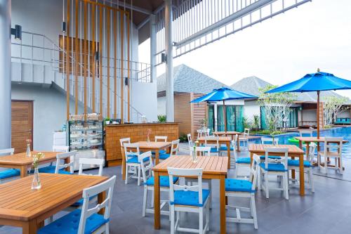 a restaurant with wooden tables and chairs and blue umbrellas at Vann Hua Hin Resort in Cha Am
