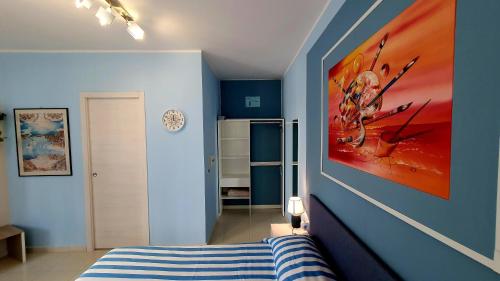 una camera da letto con pareti blu e un grande dipinto sul muro di Scilla Guest House a Scilla