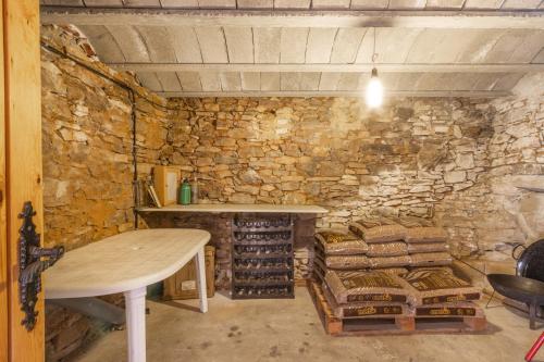 a stone wall with a table and a wine cellar at Cal Sastre in Biscarri