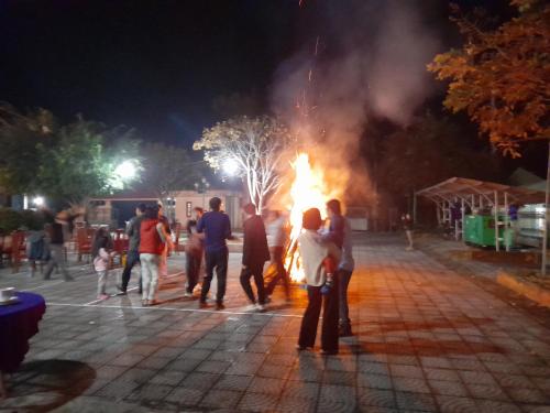 a group of people standing around a fire at night at Khách sạn Vườn Quốc gia Ba Bể in Bak Kan