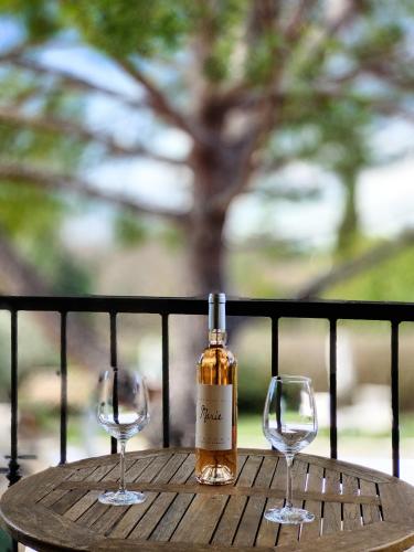 a bottle of wine and two glasses on a table at Hotel Bastide & SPA - Villa de Lourmarin in Lourmarin