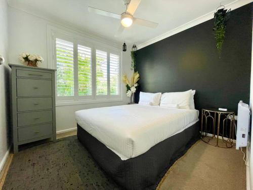 a bedroom with a large bed and a black wall at Henderson House in Wentworth Falls