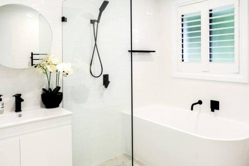 a white bathroom with a shower and a sink at Henderson House in Wentworth Falls