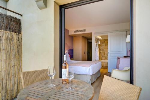a room with a table with wine glasses and a bedroom at Hotel Bastide & SPA - Villa de Lourmarin in Lourmarin