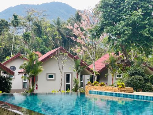 a villa with a swimming pool in front of a house at Evergreen Koh Chang Resort in Ko Chang