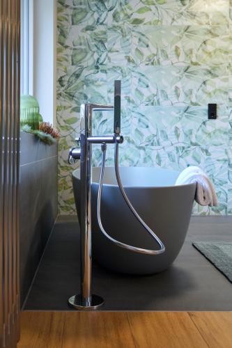 a bath tub in a bathroom with a wall at NaturPurHotel Maarblick in Meerfeld