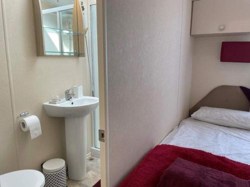 baño pequeño con lavabo y cama en 49 Bayside Cove Pevensey Bay Holiday Park en Pevensey