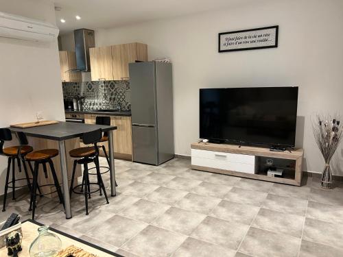 a kitchen with a television and a table with stools at Résidence Alba in Bonifacio