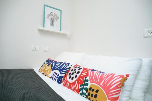 a white couch with four colorful pillows on it at Gabriel Apartments - JAFFA Street 214 Suits + Balcony in Bet HaKerem