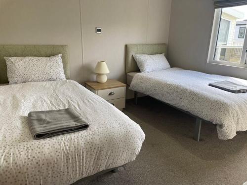 a bedroom with two beds and a table with a lamp at 42 Woodland Walk Pevensey Bay Holiday Park sleeps 6 in Pevensey