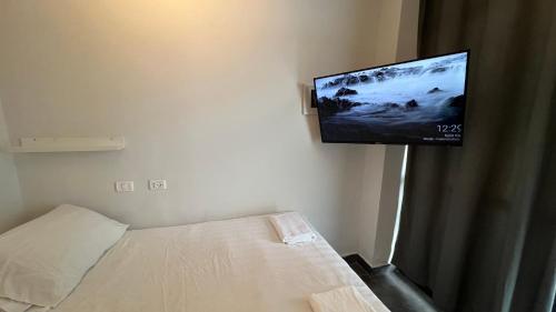 a bedroom with a bed and a flat screen tv on the wall at Gabriel Apartments - JAFFA Street 214 Suits + Balcony in Bet HaKerem