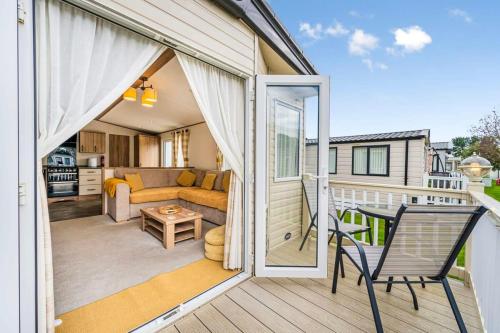 a porch with a couch and a chair on a balcony at Your Ultimate Holiday Rental at Pevensey Bay 35 Woodland Walk in Pevensey