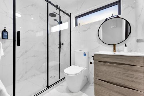 a bathroom with a shower and a toilet and a mirror at The Bays Bed & Breakfast in Auckland