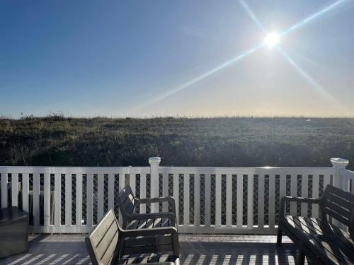 two benches on a porch with the sun in the sky at 74 Bayside Cove Pevensey Bay Holiday Park in Pevensey