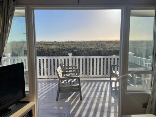 a balcony with two chairs and a television on a deck at 74 Bayside Cove Pevensey Bay Holiday Park in Pevensey