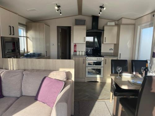 a living room and kitchen with a couch and a table at 74 Bayside Cove Pevensey Bay Holiday Park in Pevensey