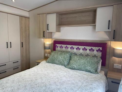 a bedroom with a bed with a purple headboard at 74 Bayside Cove Pevensey Bay Holiday Park in Pevensey