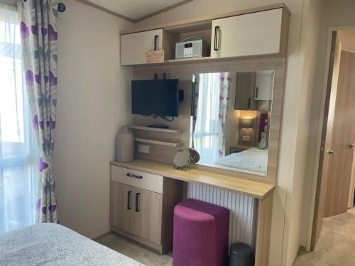 ein Schlafzimmer mit einem Waschtisch mit einem Spiegel und einem Bett in der Unterkunft 74 Bayside Cove Pevensey Bay Holiday Park in Pevensey