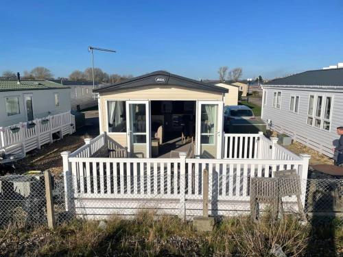 a house with a white porch with a white fence at 74 Bayside Cove Pevensey Bay Holiday Park in Pevensey