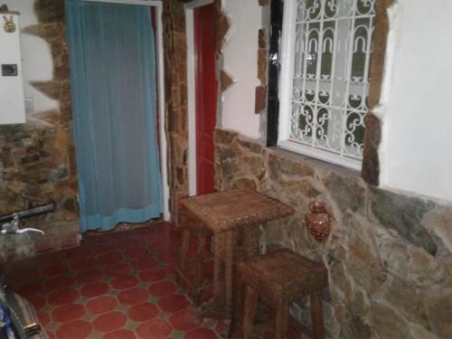 a kitchen with a table and two stools in a room at Maison d hôtes Tioute Chez Abdelmajid in Tiout