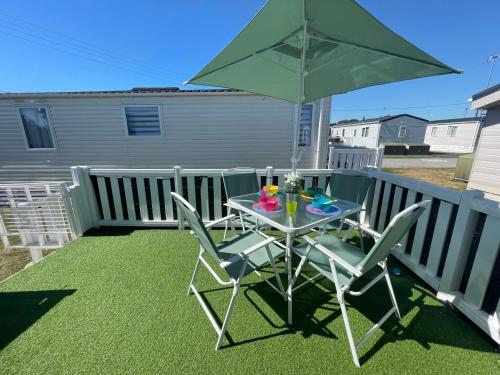 a table and chairs with a green umbrella on a balcony at 27 Tower View Pevensey Bay Holiday Park in Pevensey