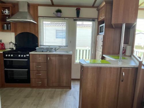 a kitchen with wooden cabinets and a sink and a stove at 27 Tower View Pevensey Bay Holiday Park in Pevensey