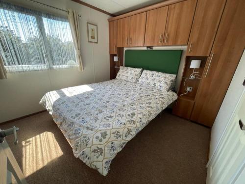a bedroom with a large bed with a green headboard at 27 Tower View Pevensey Bay Holiday Park in Pevensey