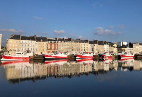 a group of boats docked in a harbor with buildings at LA FERME DE NEHOU in Gatteville-le-Phare