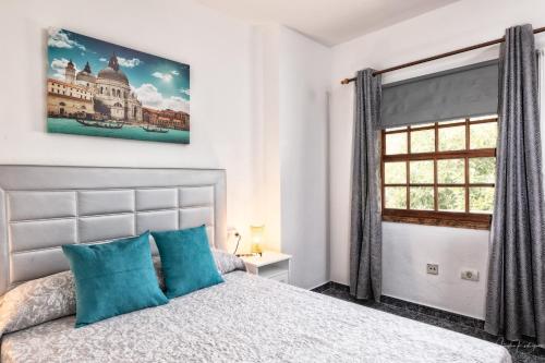ein Schlafzimmer mit einem Bett mit blauen Kissen und einem Fenster in der Unterkunft Lightbooking Luymar Villa de Mazo con piscina in Mazo