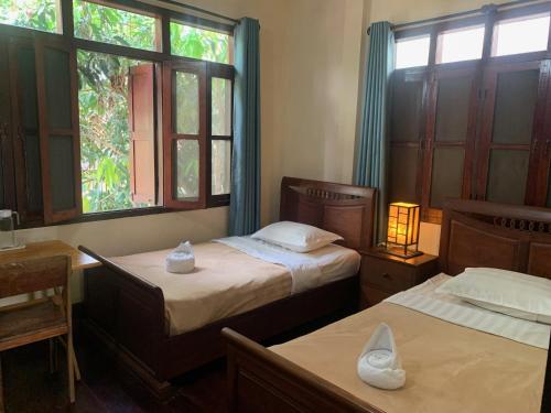 1 dormitorio con 2 camas y ventana en Manichan Guesthouse, en Luang Prabang