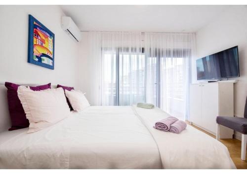 a bedroom with a large white bed with a large window at S`akvarel 7 - new & modern studio in Split