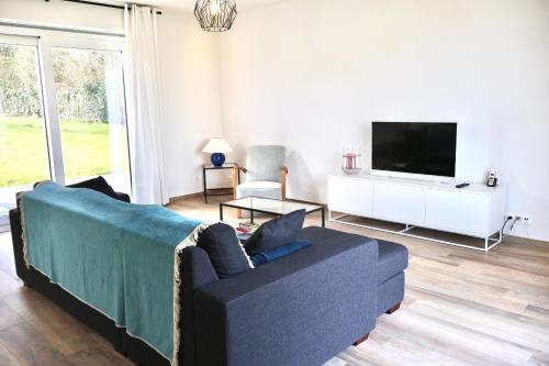 a living room with a blue couch and a tv at La Lumineuse in Tardinghen