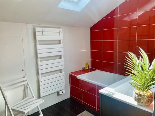 - une salle de bains rouge avec une baignoire blanche et une plante dans l'établissement Villa Les coquelicots La Baule, à La Baule