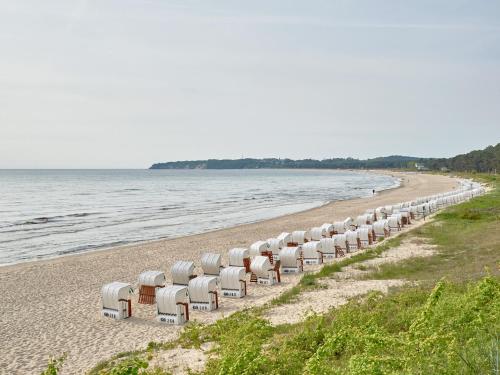 uma fila de cadeiras numa praia junto à água em Strandwohnungen Sellin - WG04 mit 2 Balkonen em Ostseebad Sellin