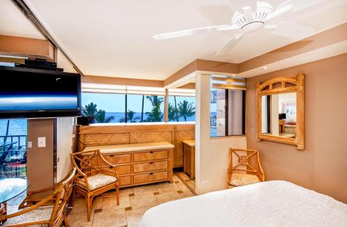 1 dormitorio con cama, escritorio y ventana en Kealia Resort 402, en Kihei