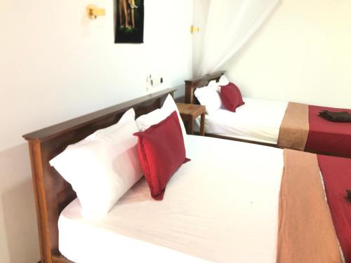 a bedroom with two beds with red and white pillows at Sigiriya Moonlight Home in Sigiriya