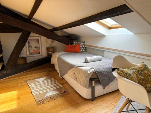 Schlafzimmer im Dachgeschoss mit einem Bett und einem Stuhl in der Unterkunft ღ La Cabane Rochelaise • Vue sur le vieux-port in La Rochelle