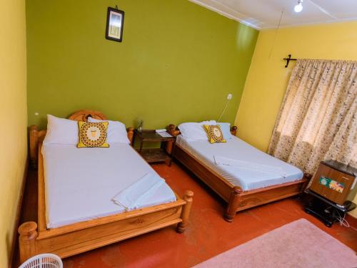 Zimmer mit 2 Betten und einem TV. in der Unterkunft FARAJA HOMESTAY- Seamless Comfort in the Heart of the City - Free WiFi, Warm Hospitality, and Local Delights Await in Moshi