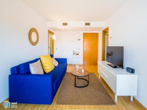 uma sala de estar com um sofá azul e uma televisão em Apto Diana em Platja d'Aro