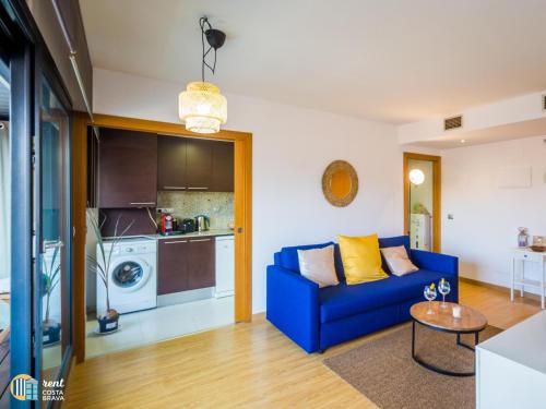 uma sala de estar com um sofá azul e uma cozinha em Apto Diana em Platja d'Aro