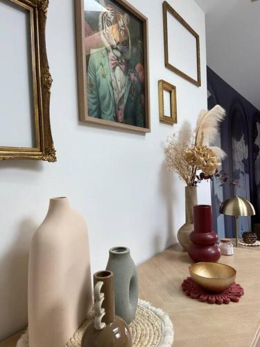 a table with vases and a painting on the wall at L'Atelier 48 in Langueux