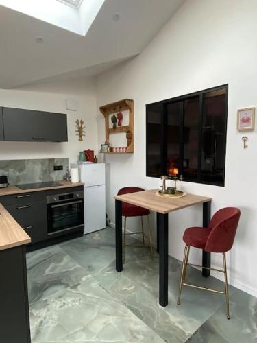 a kitchen with a table and two red chairs at L'Atelier 48 in Langueux