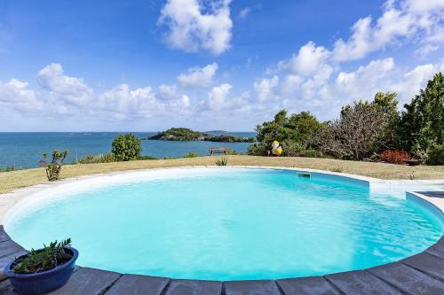 una gran piscina azul con vistas al agua en Maison d'Ô Pointe Thalémont, avec petite crique privative en Le François