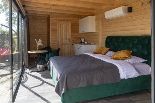 a bedroom with a green bed in a wooden room at Doles Perle in Ķekava
