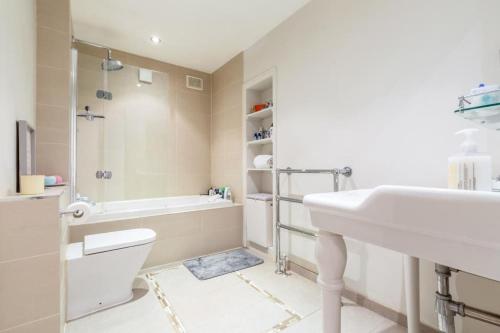 a bathroom with a sink and a tub and a toilet at Bright 2BR Flat, 5 min to South Wimbledon Tube St in London