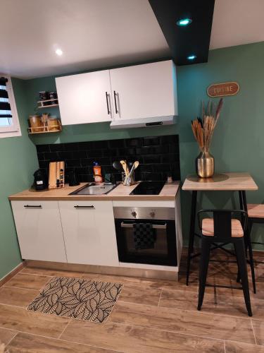 - une cuisine avec des placards blancs, un évier et une table dans l'établissement Château de la sagesse SPA, à Rouen