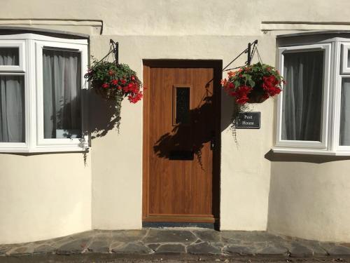 una casa con una porta in legno e due finestre di The Post House (Centre of riverside village) a Stoke Gabriel