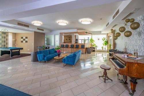 a living room with a pool table and blue chairs at Hotel Vital in Zalakaros